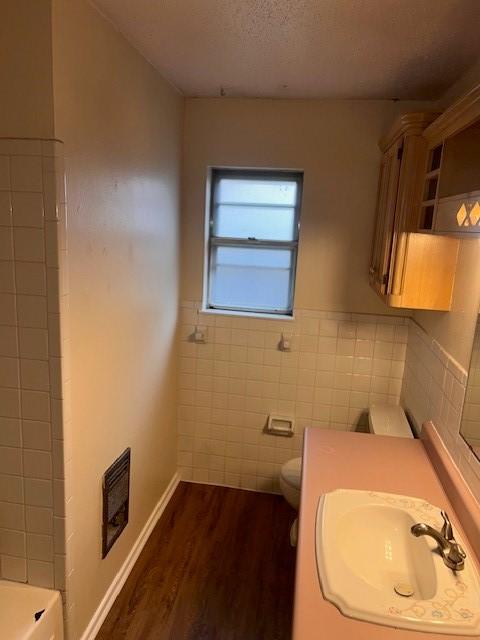 full bath featuring a sink, tile walls, toilet, wood finished floors, and visible vents