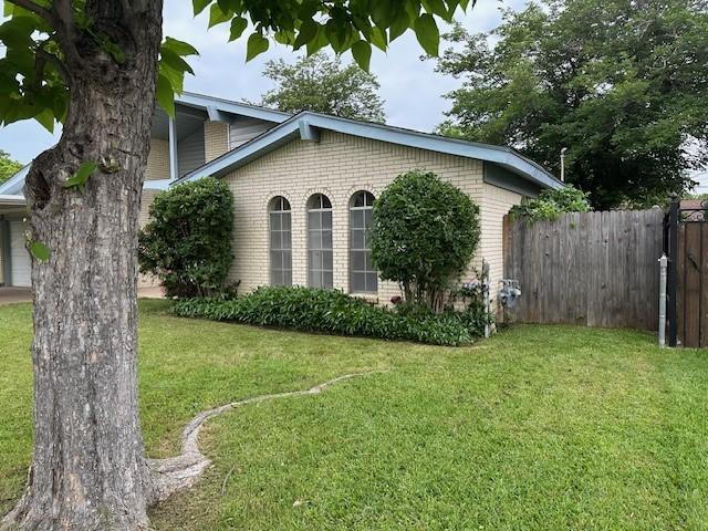 view of home's exterior with brick siding, fence, and a lawn