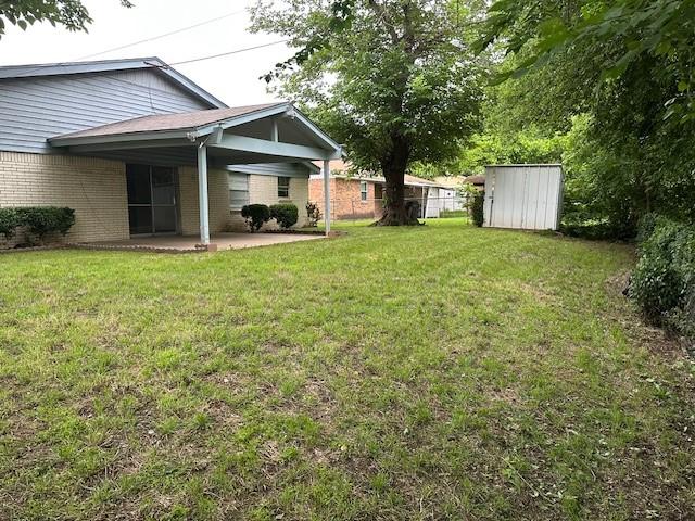 view of yard with an outbuilding, a patio, and a shed