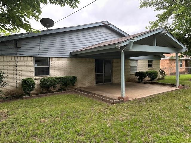 back of house featuring a patio area, brick siding, and a lawn