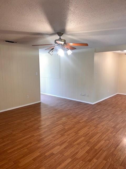 unfurnished room with a textured ceiling, a ceiling fan, visible vents, and wood finished floors
