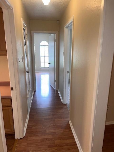 hallway with baseboards and dark wood-style floors