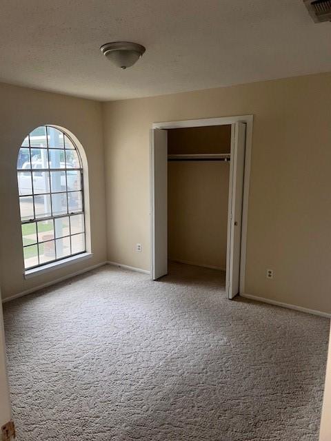 unfurnished bedroom featuring carpet flooring, a closet, visible vents, and baseboards