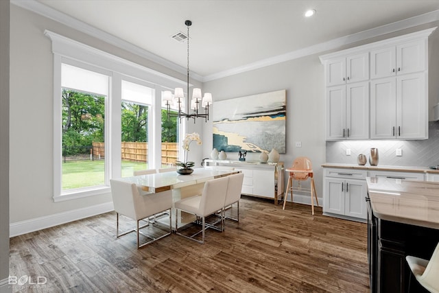 dining area featuring visible vents, dark wood-style flooring, baseboards, a chandelier, and ornamental molding