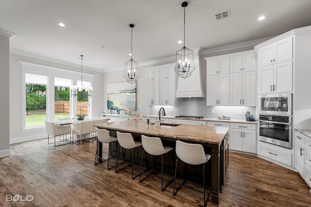 kitchen with an inviting chandelier, stainless steel appliances, visible vents, and crown molding