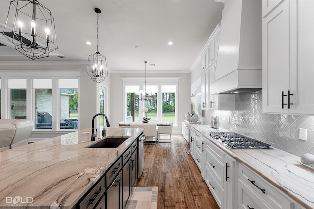 kitchen featuring an inviting chandelier, a sink, stainless steel appliances, custom exhaust hood, and ornamental molding