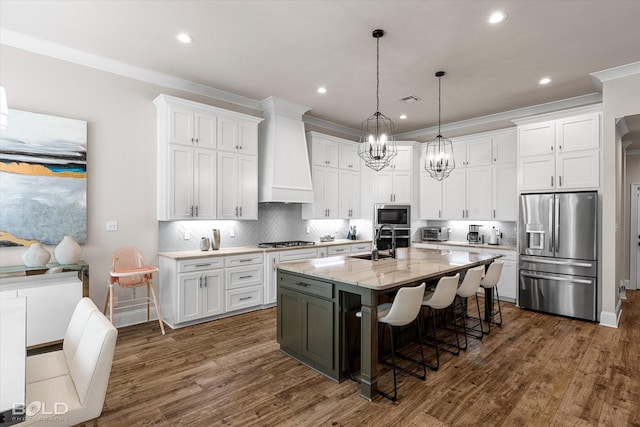 kitchen with a breakfast bar, a sink, stainless steel appliances, white cabinetry, and custom exhaust hood