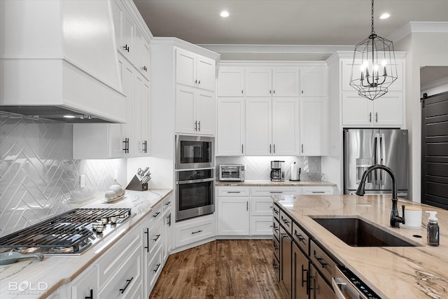 kitchen featuring white cabinetry, premium range hood, appliances with stainless steel finishes, and a sink