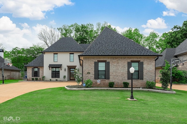 french country inspired facade with roof with shingles, brick siding, and a front yard