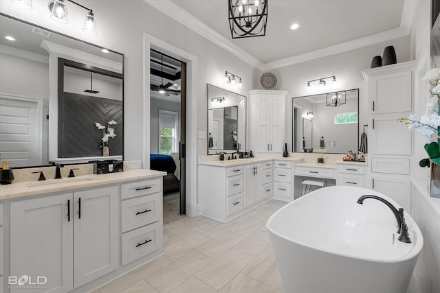 full bathroom featuring a sink, ornamental molding, two vanities, and a freestanding tub
