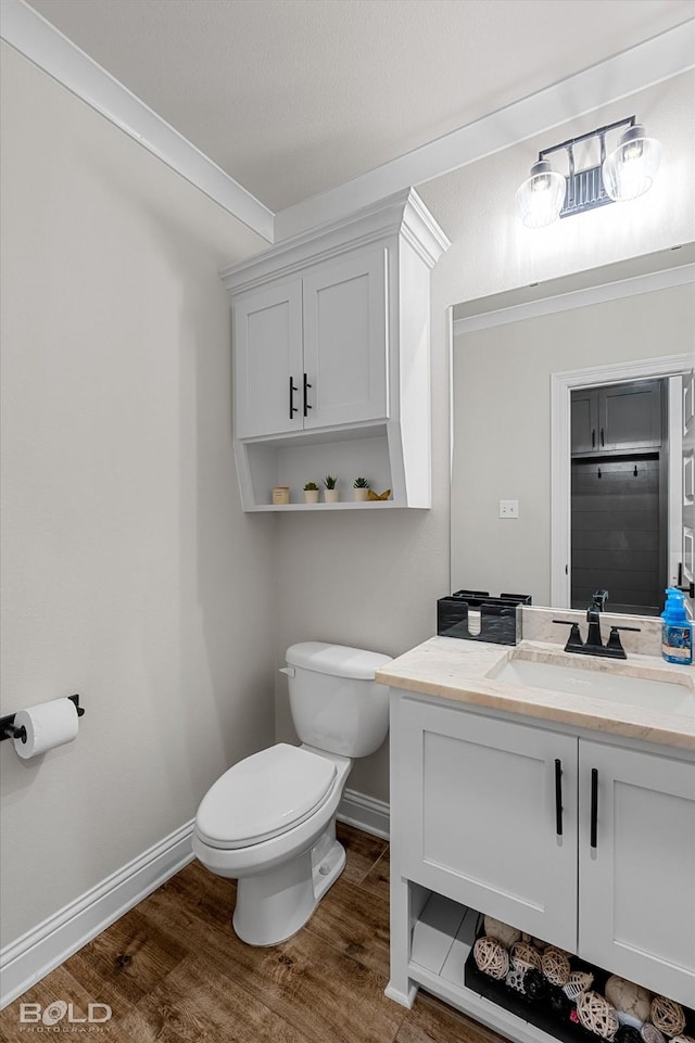 bathroom featuring vanity, toilet, baseboards, and wood finished floors