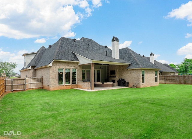 rear view of house with a patio area, brick siding, a fenced backyard, a lawn, and a shingled roof