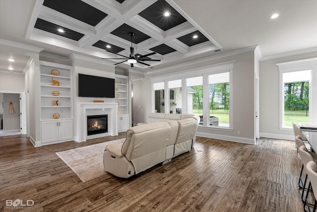 living room featuring a wealth of natural light, a ceiling fan, ornamental molding, and a glass covered fireplace