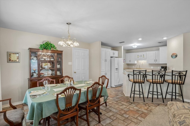 dining space featuring a notable chandelier, visible vents, baseboards, brick floor, and recessed lighting