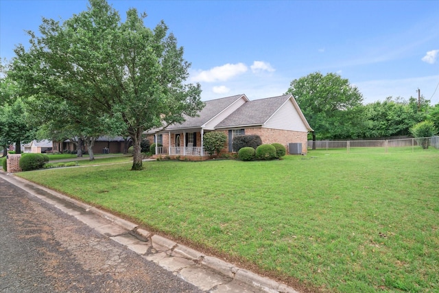 view of front facade featuring brick siding, a porch, fence, and a front yard