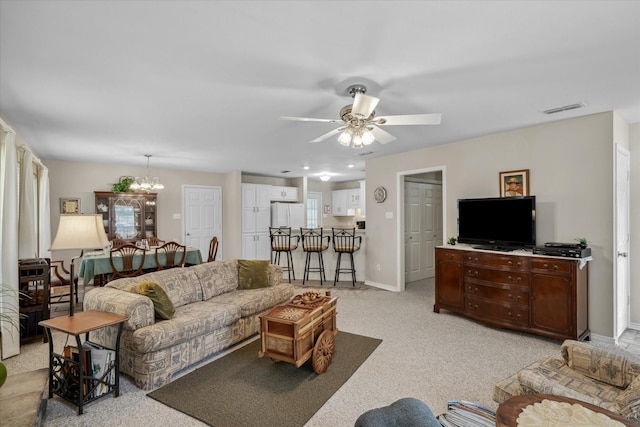 living room with light colored carpet, ceiling fan with notable chandelier, baseboards, and visible vents