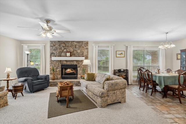 living room featuring a fireplace, a ceiling fan, and stone tile floors