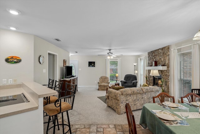 living room with a ceiling fan, stone finish floor, baseboards, visible vents, and a fireplace