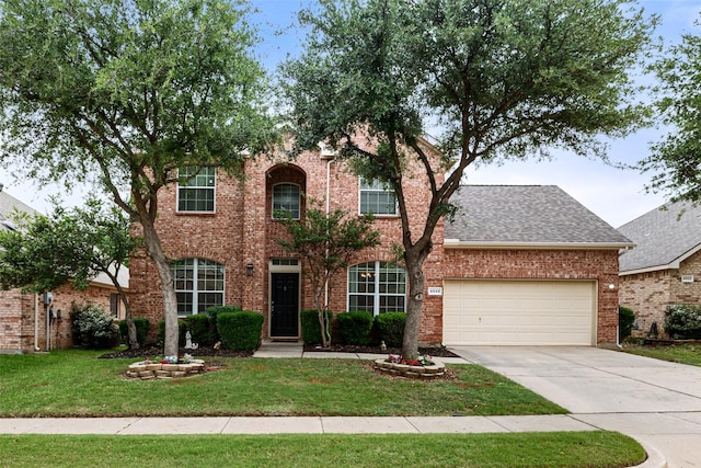 view of front of house with a front lawn, concrete driveway, an attached garage, brick siding, and roof with shingles