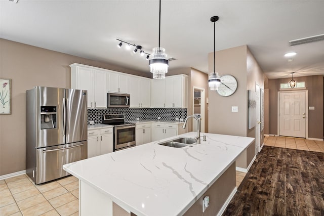 kitchen with stainless steel appliances, a sink, baseboards, backsplash, and white cabinets