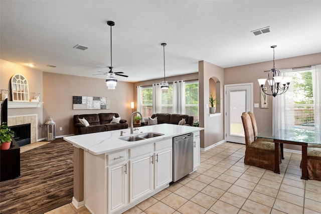 kitchen with a sink, stainless steel dishwasher, open floor plan, baseboards, and white cabinets