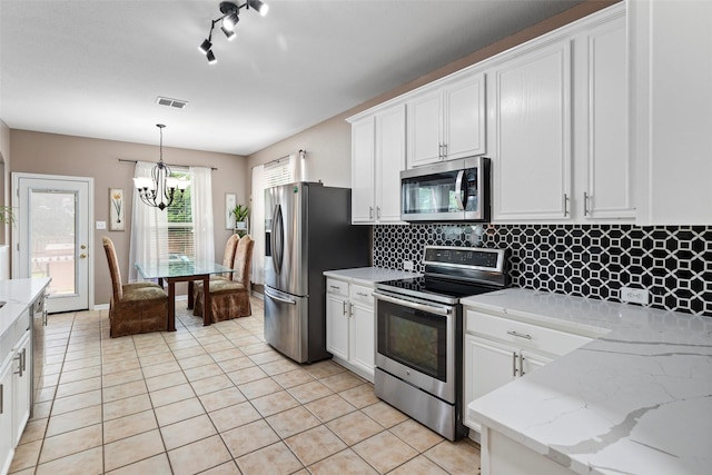 kitchen with stainless steel appliances, light tile patterned floors, a chandelier, white cabinetry, and decorative backsplash