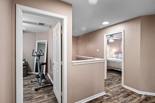 corridor featuring dark wood finished floors, a textured wall, and baseboards