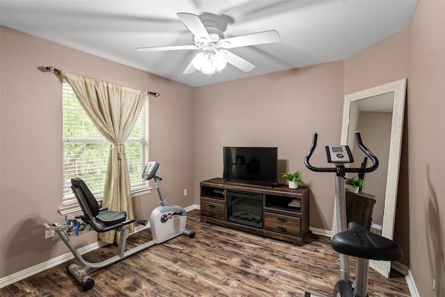 exercise room featuring wood finished floors, a ceiling fan, and baseboards
