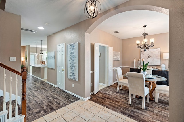 foyer with arched walkways, wood finished floors, a chandelier, and stairs