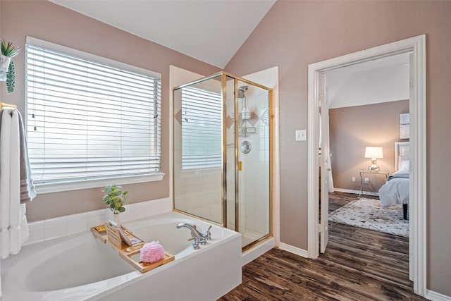 ensuite bathroom with a stall shower, a garden tub, lofted ceiling, wood finished floors, and baseboards