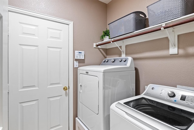 laundry area with separate washer and dryer and a textured wall
