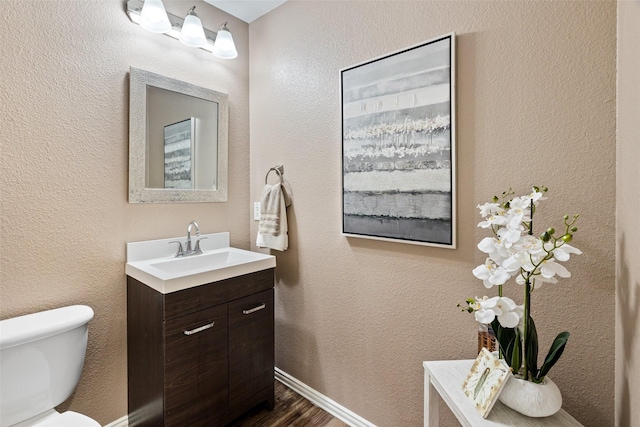 bathroom featuring toilet, wood finished floors, and vanity