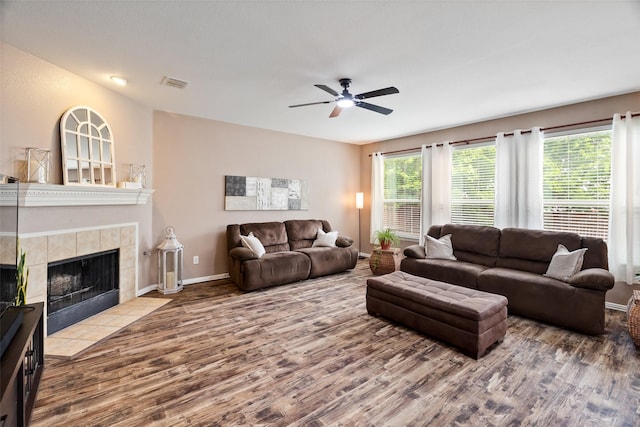 living area featuring wood finished floors, ceiling fan, baseboards, and a tiled fireplace