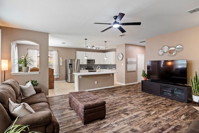 living area featuring a ceiling fan, wood finished floors, baseboards, and arched walkways