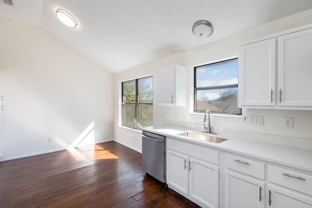 kitchen with lofted ceiling, stainless steel dishwasher, a textured ceiling, a sink, and white cabinets