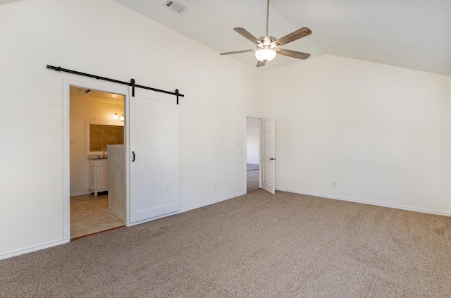unfurnished bedroom featuring a barn door, baseboards, ensuite bath, visible vents, and light carpet