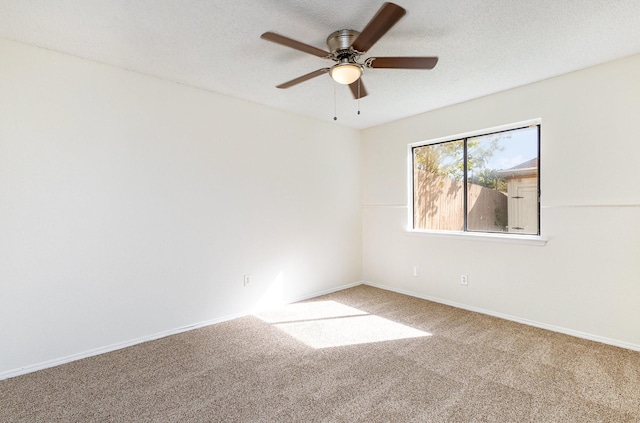 carpeted spare room with a ceiling fan, baseboards, and a textured ceiling