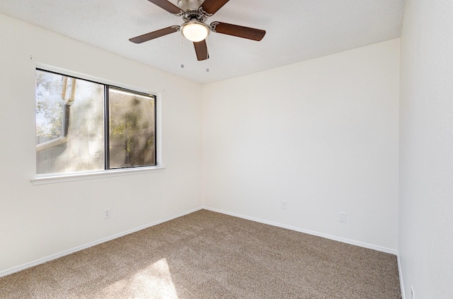 carpeted empty room with ceiling fan and baseboards
