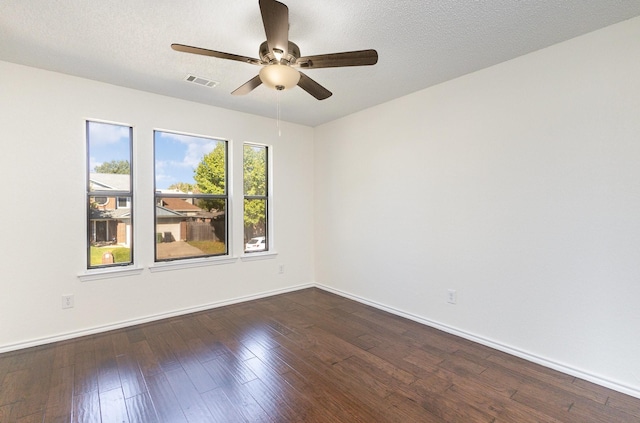empty room featuring baseboards, a ceiling fan, visible vents, and dark wood finished floors
