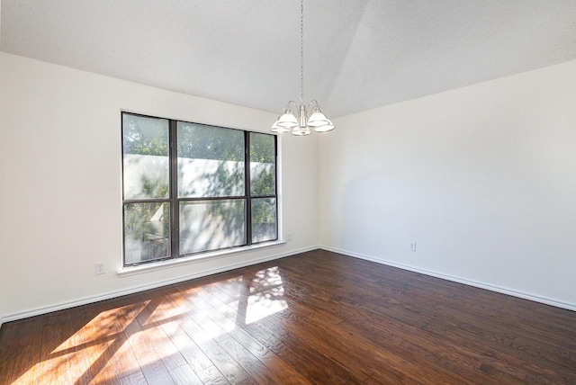 spare room featuring an inviting chandelier, baseboards, and dark wood-style floors