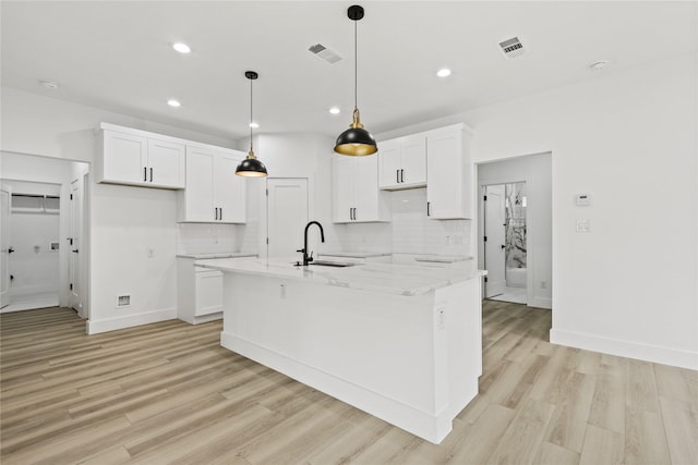7819 Brownsville Ave, Dallas, TX 75216 - kitchen featuring tasteful backsplash, visible vents, a sink, white cabinets, and an island with sink