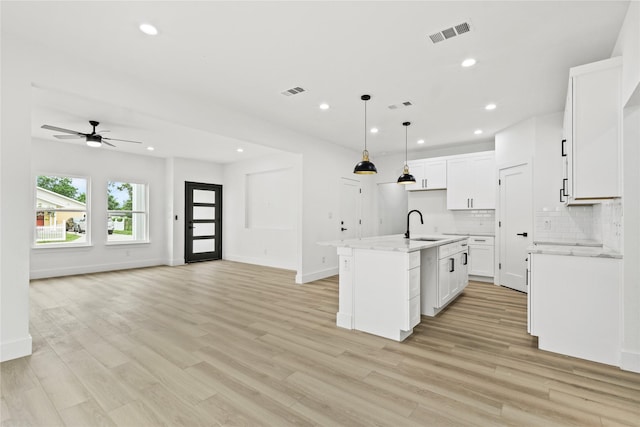 7819 Brownsville Ave, Dallas, TX 75216 - kitchen featuring a kitchen island with sink, visible vents, light wood-style flooring, open floor plan, and a ceiling fan