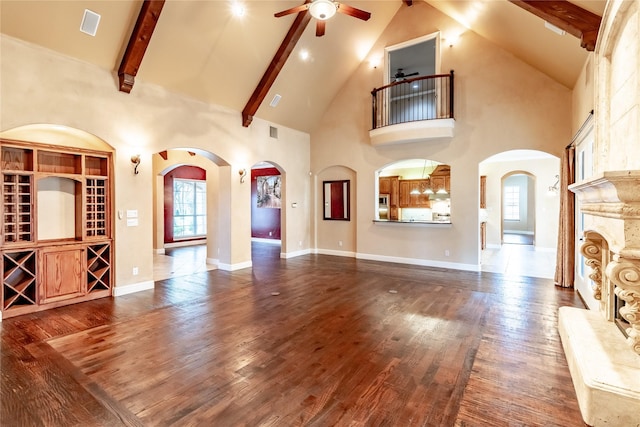 unfurnished living room featuring ceiling fan, arched walkways, high vaulted ceiling, and wood finished floors