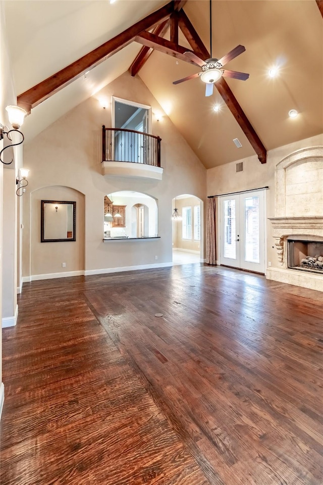unfurnished living room featuring french doors, high vaulted ceiling, ceiling fan, a large fireplace, and beamed ceiling