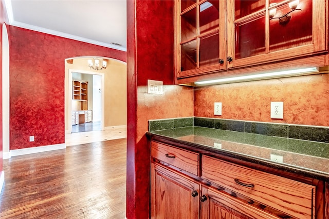 kitchen with glass insert cabinets, ornamental molding, visible vents, a chandelier, and dark wood-type flooring