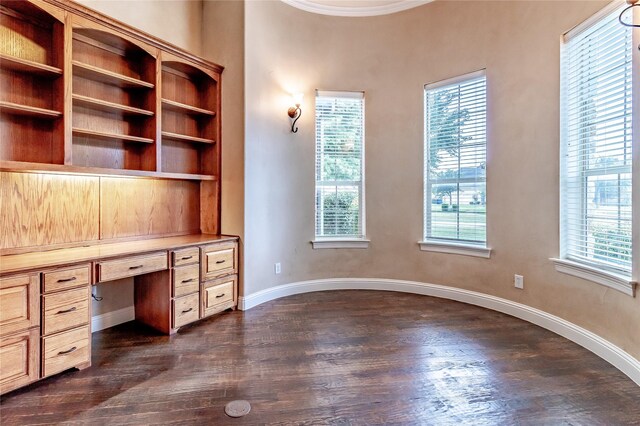 unfurnished office featuring dark wood-style flooring, plenty of natural light, and built in study area