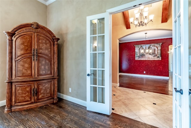 interior space with french doors, wood finished floors, a chandelier, crown molding, and arched walkways