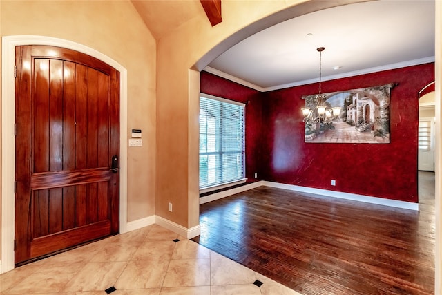foyer entrance with arched walkways, tile patterned flooring, a chandelier, and baseboards