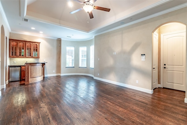 unfurnished living room featuring dark wood-style floors, ornamental molding, arched walkways, and indoor bar