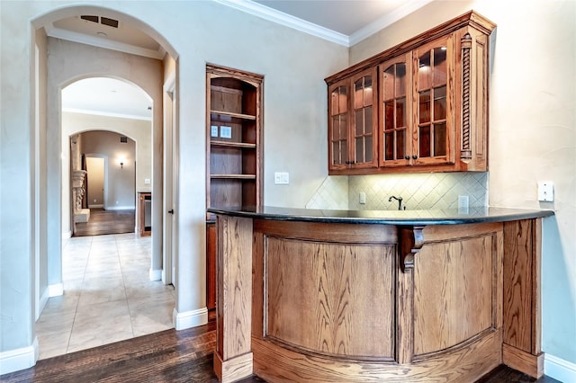 bar featuring wet bar, baseboards, and ornamental molding